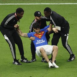 Un aficionado salta al césped con una bandera arcoíris