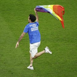 Un aficionado salta al césped con una bandera arcoíris
